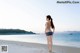 A woman walking on a beach next to the ocean.