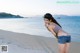 A woman standing on a beach next to the ocean.