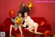 three girls sitting on a red couch with gold balloons