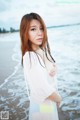 A woman standing on a beach next to the ocean.