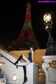 A woman sitting on the steps of a building in front of the Eiffel Tower.