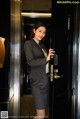 A woman in a business suit standing in an elevator.