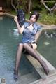 A woman sitting on the edge of a pool holding a fan.