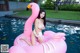 A woman in a white bikini sitting on a pink flamingo float.