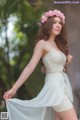 A woman in a white dress with a flower crown on her head.