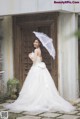 A woman in a wedding dress holding an umbrella.