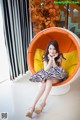 A woman sitting in an orange and yellow chair.