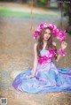 A woman in a blue dress sitting on a swing with flowers in her hair.