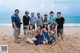 A group of people posing for a picture on the beach.