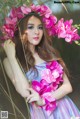 A woman in a purple dress holding a bunch of pink flowers.