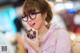 A woman wearing glasses eating a donut in a restaurant.