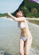 A woman in a white bikini standing in the water.