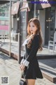 A woman in a black dress is walking down the street.