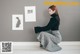 A woman sitting on the floor in front of a wall with pictures on it.