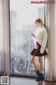 A woman standing in front of a window looking at her phone.