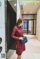 A woman in a red lace dress is holding a blue purse.