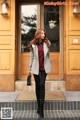 A woman is standing in front of a building.