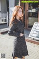 a woman in a black dress is walking down the street