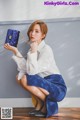 A woman in a white shirt and blue skirt holding a blue purse.