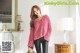 A woman in a pink sweater and black pants posing for a picture.