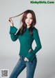 A woman in a green sweater and jeans posing for a picture.