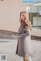 A woman in a gray coat is walking down the street.