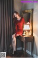 A woman in a red dress sitting on a table next to a lamp.