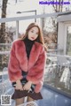 a woman in a pink fur coat sitting on a chair