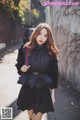 A woman in a black dress and fur coat is walking down the street.