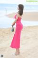 A woman in a pink dress standing on a beach.