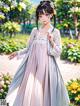 A woman in a long dress standing in a park.