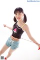 A woman in shorts and a tank top holding a skipping rope.