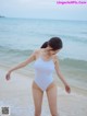 A woman in a white bathing suit standing on the beach.