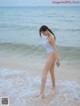 A woman in a white bathing suit standing in the ocean.