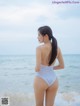 A woman in a white bathing suit standing on the beach.