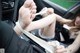 A woman sitting in the back seat of a car with her feet tied up.