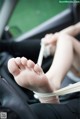 A woman's feet tied up in a car seat.