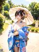 A woman in a blue kimono holding an umbrella.