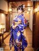 A woman in a blue kimono standing in a hallway.