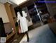 A woman in a white coat is walking through a hotel room.