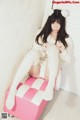 A woman sitting on top of a pink and white ottoman.