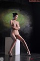 A naked woman sitting on top of a white box.