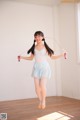 A young girl in a white leotard and blue shorts holding a skipping rope.