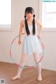 A young girl in a white dress holding a hula hoop.