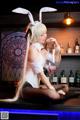 A woman in bunny ears sitting on a bar with a glass of wine.