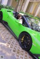 A woman sitting in the driver's seat of a green sports car.