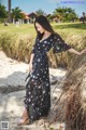 A woman in a black dress standing on a beach.