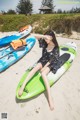 A woman sitting on top of a green and blue surfboard.