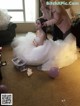 A woman in a wedding dress sitting on the floor next to a woman.