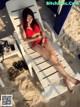 A woman in a red bikini laying on a beach chair.